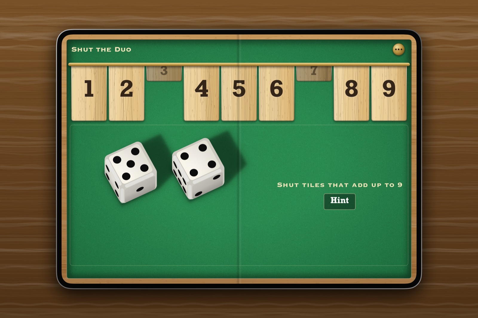 Shut the Duo on an open iPhone Duo lying on dark wood: the tiles along the top of the felt, and two dice.